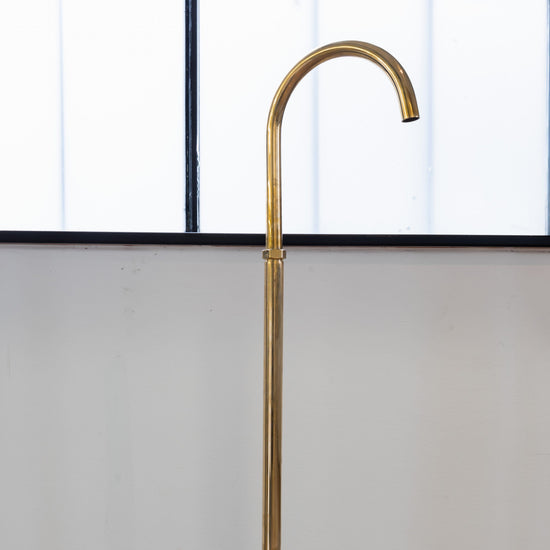 Francone BT67 unlacquered brass floor-mounted bathroom faucet with a curved gooseneck spout.