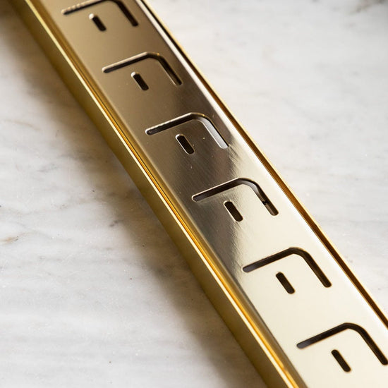 Francone BTA17 linear shower drain showcases the unlacquered brass finish and slotted grate detail.