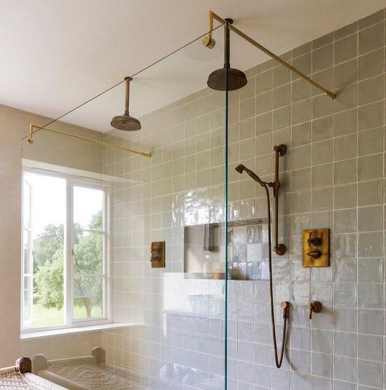 An installed Francone BTS25 unlacquered brass sliding rail hand shower in a tiled luxury bathroom.