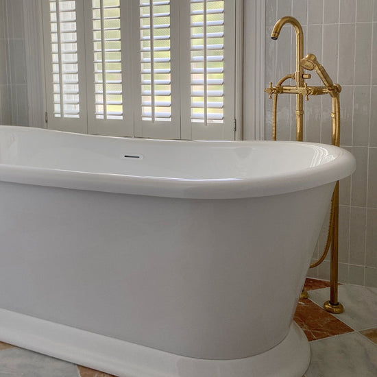 Francone BT22F traditional unlacquered brass floor-mounted bath faucet installed beside a white freestanding tub.