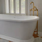 Francone BT22F traditional unlacquered brass floor-mounted bath faucet installed beside a white freestanding tub.