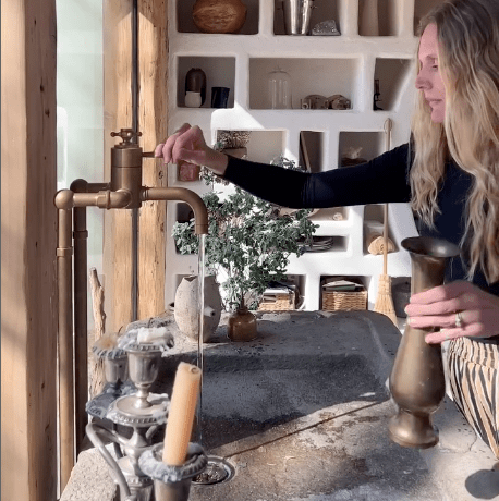 A woman turns on the vintage Francone BT34TF unlacquered brass floor-mounted thermostatic bath faucet.