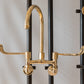 Francone BT49LW wall-mounted kitchen faucet in unlacquered brass with a curved swivel spout and long levers.