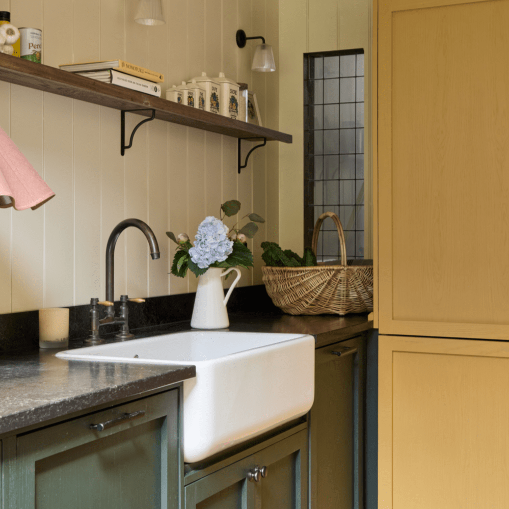 An installed Francone BT49Y traditional gunmetal kitchen faucet with a curved swivel spout over a white farm sink.