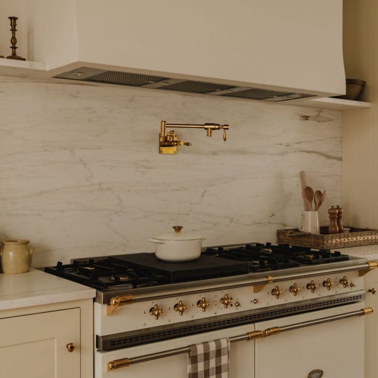 Traditional Francone BT6 unlacquered brass wall-mounted kitchen pot filler faucet installed over a range.
