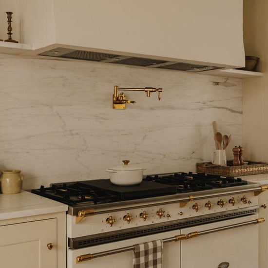 Traditional Francone BT6 unlacquered brass wall-mounted kitchen pot filler faucet installed over a range.