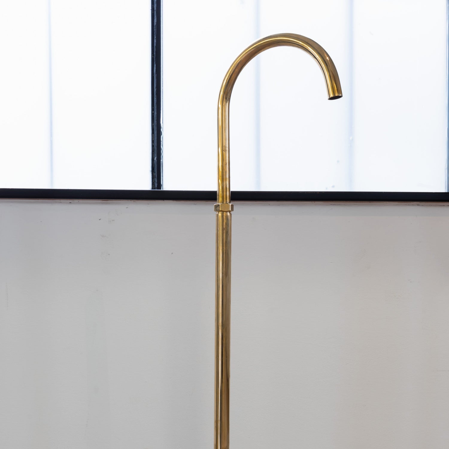 Francone BT67 unlacquered brass floor-mounted bathroom faucet with a curved gooseneck spout.