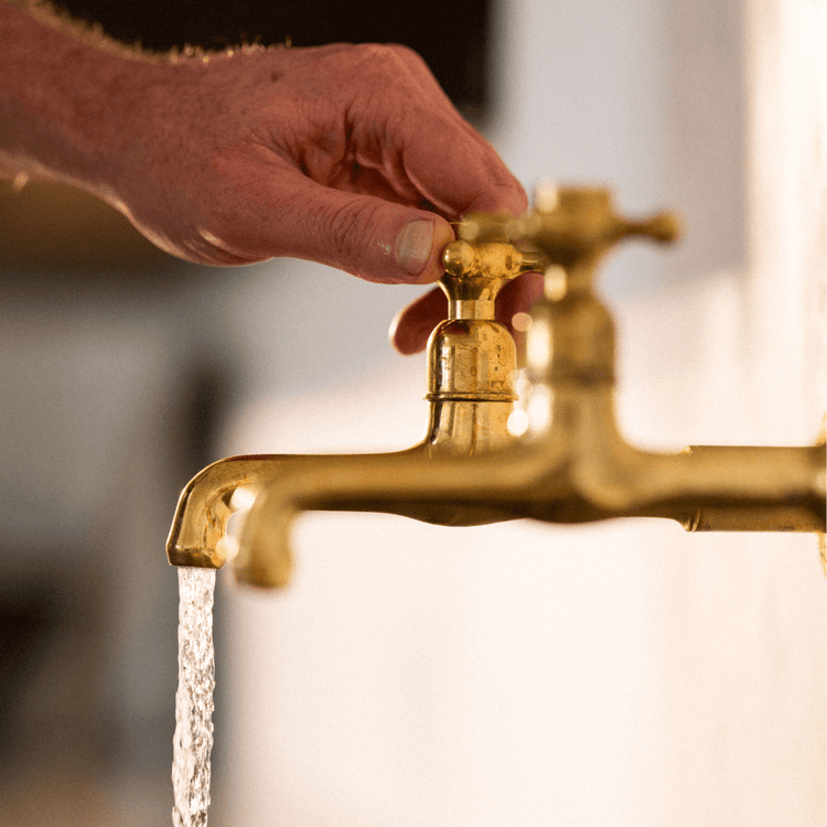 A hand turning a traditional Francone BT72 solid brass wall-mounted bathroom faucet.