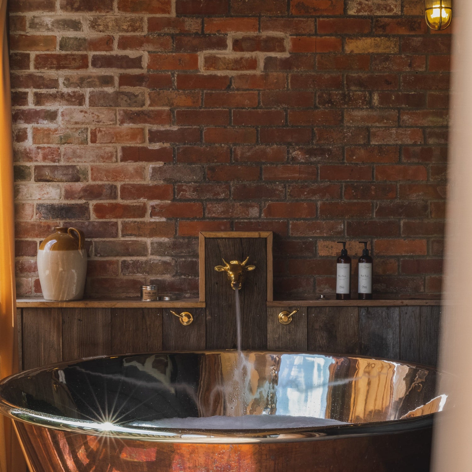 An artisan Francone BT85 unlacquered brass bull head tap faucet installed in a rustic bathroom.