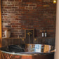 An artisan Francone BT85 unlacquered brass bull head tap faucet installed in a rustic bathroom.