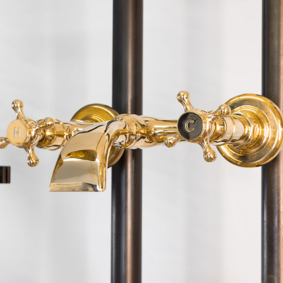 Francone BT89 wall-mounted bath filler faucet in unlacquered brass with a custom spout and traditional cross handles.