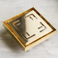 A square Francone BTA14 unlacquered brass shower drain waste is shown on a light marble surface.