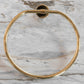 Francone BTA23 circular solid brass towel holder in unlacquered brass, mounted on a marble bathroom wall.