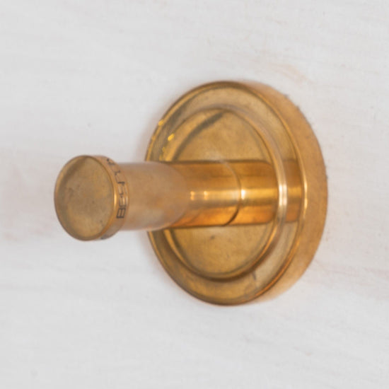 A Francone BTA35 round single robe hook in unlacquered brass, perfect for elegant bathroom accessories.