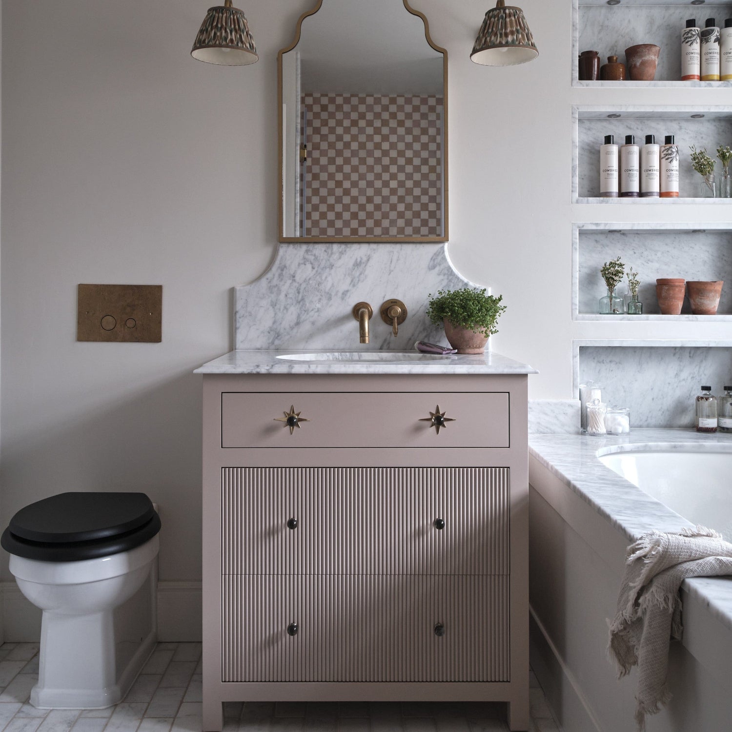 An installed Francone BTA6 unlacquered brass toilet dual flush plate on a bathroom wall by Millie Turner