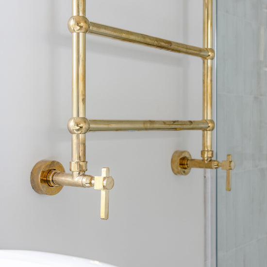 A traditional Francone BTR16 unlacquered brass heated towel rail installed in a bathroom.