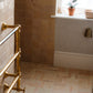 An unlacquered brass Francone BTR2 classic heated towel rail installed in a traditional bathroom.