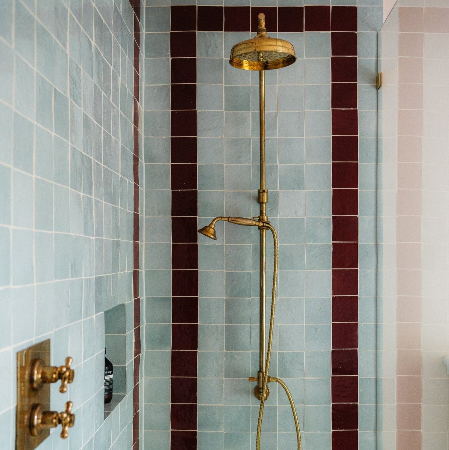 A vintage Francone BTS18 unlacquered brass thermostatic shower column installed in a blue tiled bathroom.