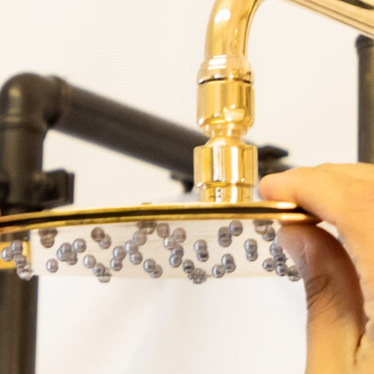 A hand adjusting the circular Francone BTS1H slim unlacquered brass shower head.