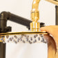A hand adjusting the circular Francone BTS1H slim unlacquered brass shower head.