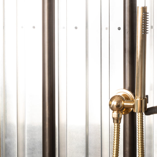 Detail of the Francone BTS23M unlacquered brass wall mounted hand held shower on a minimalist riser rail.