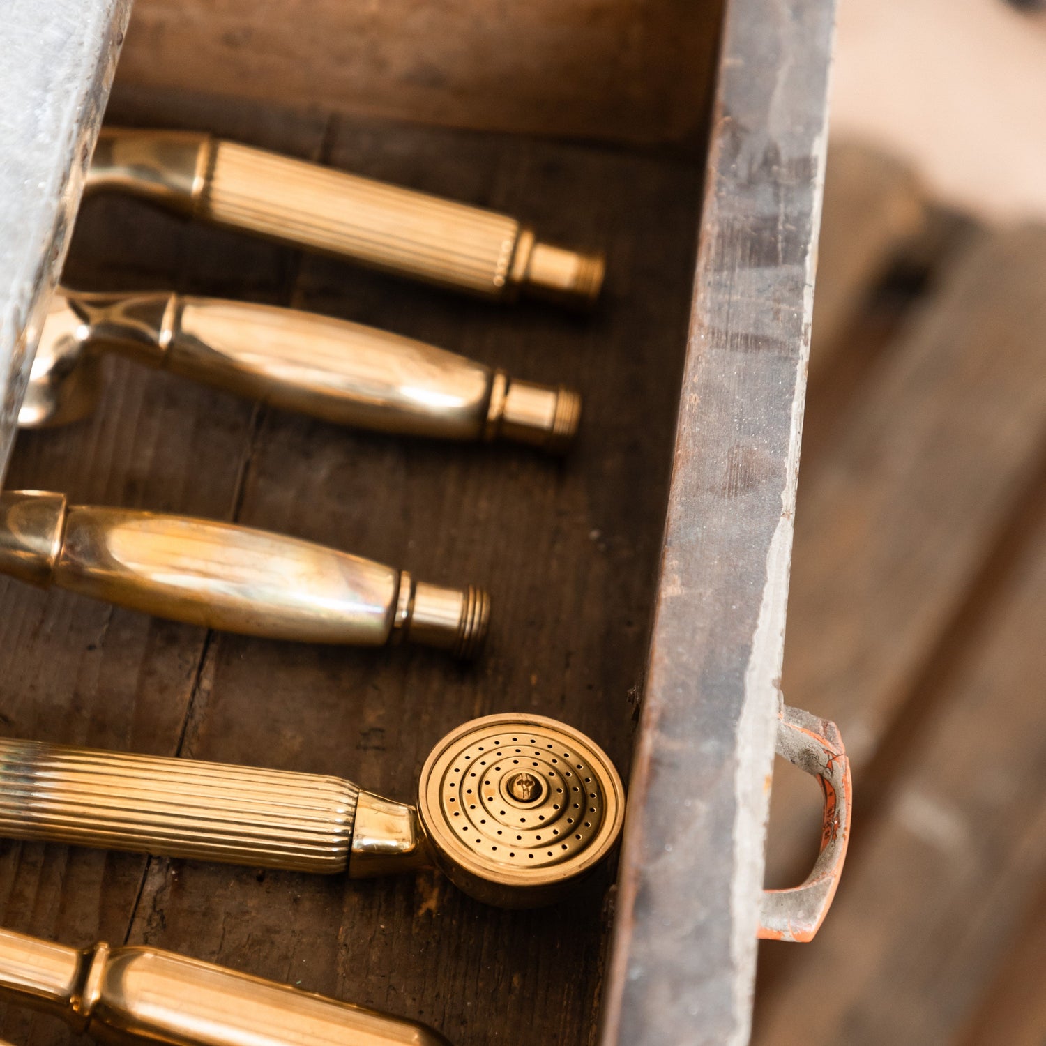 Bespoke solid brass Francone BTS26 traditional hand shower handles displayed in a rustic wooden drawer.