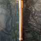 A Francone BTSA solid brass ceiling-mounted shower arm in unlacquered brass against a green marble wall.