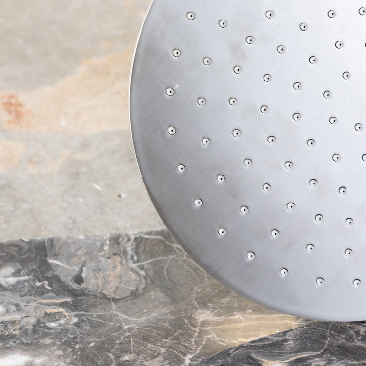 Detail of the handcrafted solid brass Francone SSS17 circular shower head in a luxury bathroom.
