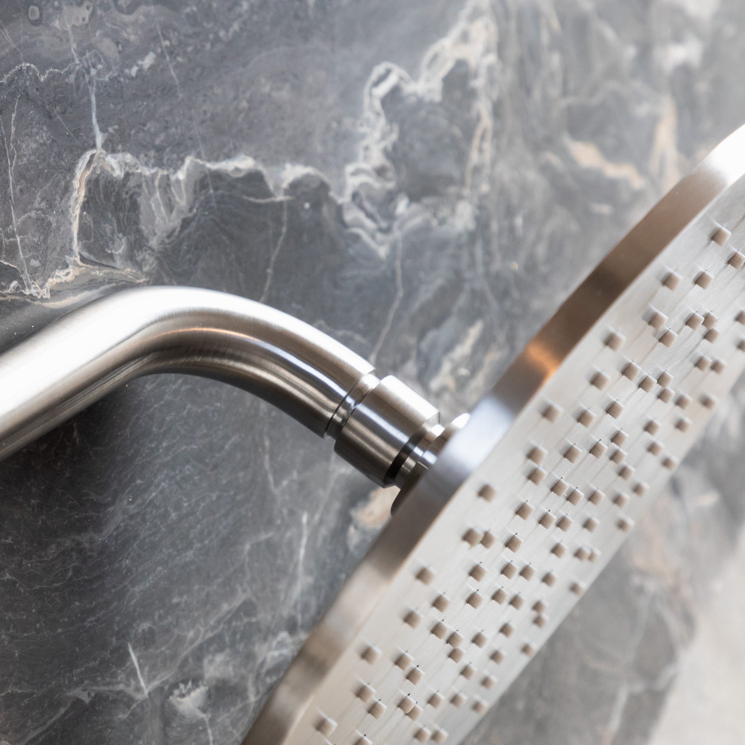A close-up detail of the Francone SSS6 solid brass circular wall-mounted shower head and curved arm.