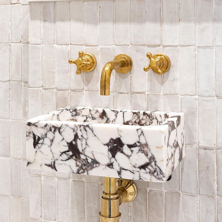 Installed Francone BT34 wall-mounted unlacquered brass faucet and double-handle taps over a marble basin, styled by Vacay Co.