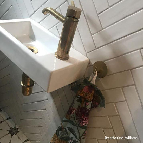 A Francone BT64 unlacquered brass deck-mounted mixer faucet installed on a small basin with vintage patina.