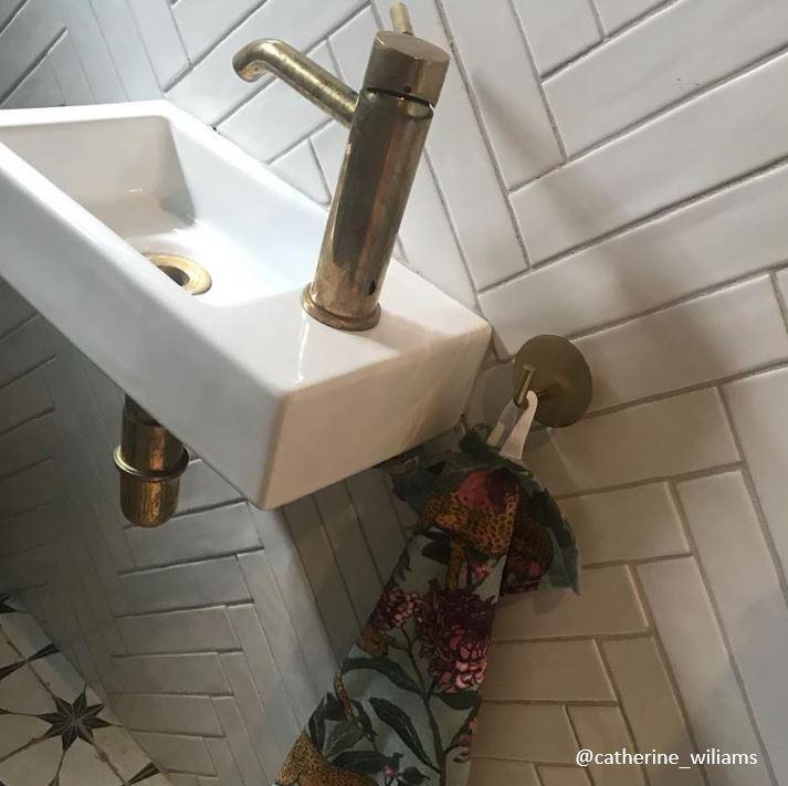 A Francone BT64 unlacquered brass deck-mounted mixer faucet installed on a small basin with vintage patina.