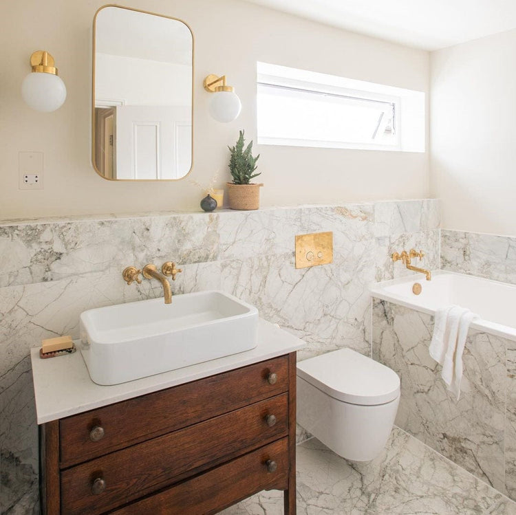 The Francone BT70 wall-mounted brass tap, a traditional bathroom faucet, installed over a white washbasin.