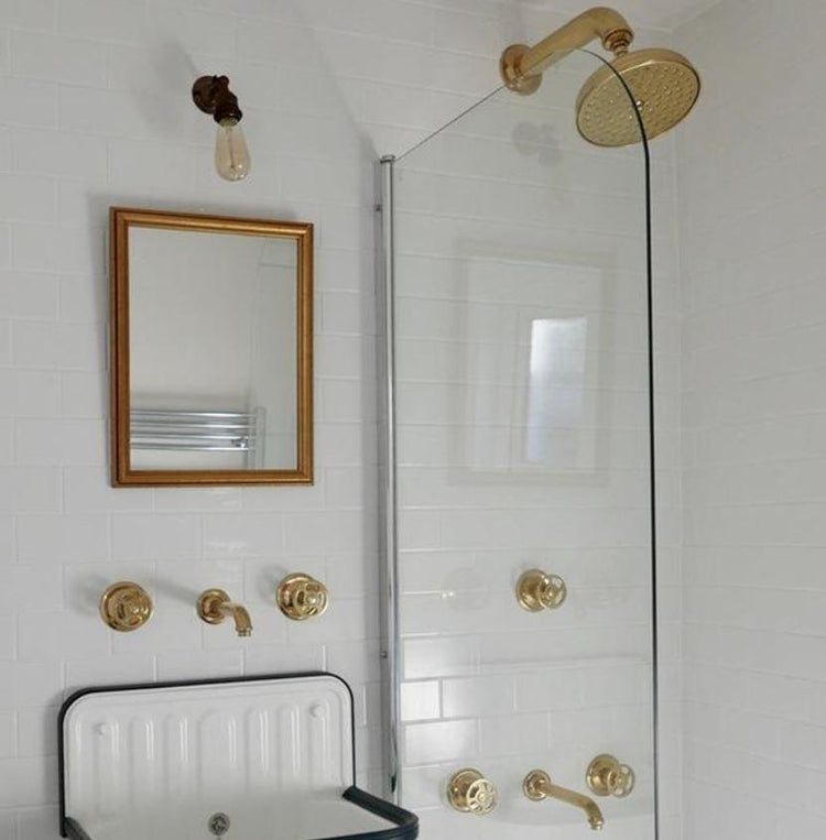Unlacquered brass Francone BTA5 wall-mounted shower diverter installed in a white tiled bathroom.