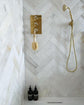 Francone BTS23 unlacquered brass wall-mounted hand shower installed on white marble herringbone tile by Victoria at the White Cottage.