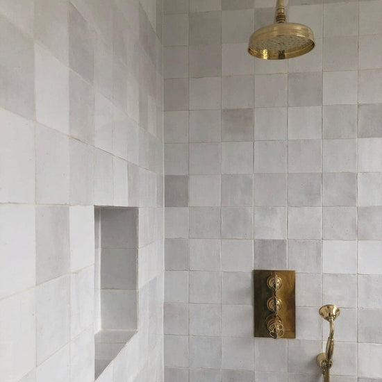 An unlacquered brass Francone BTS32 dual control thermostatic wall mounted shower installed in a tiled bathroom.